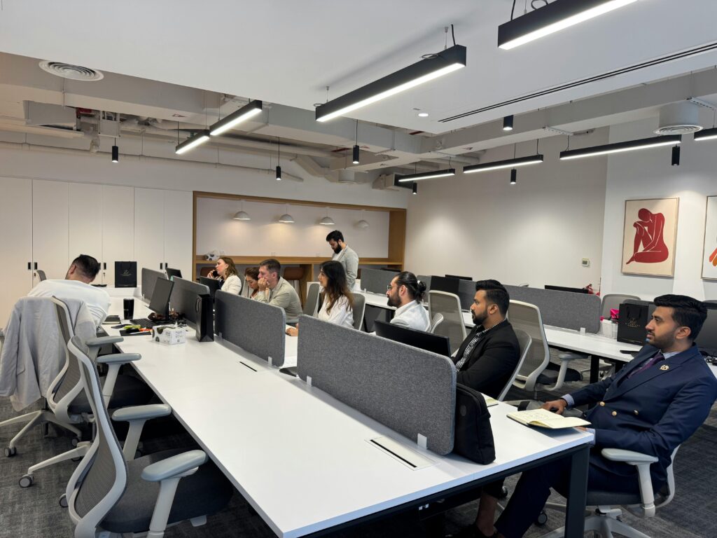 Diverse team working in a modern office setting with computers and collaborative spaces.